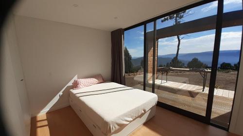 a bedroom with a bed and a large glass window at Bungalow com piscina in Celorico de Basto