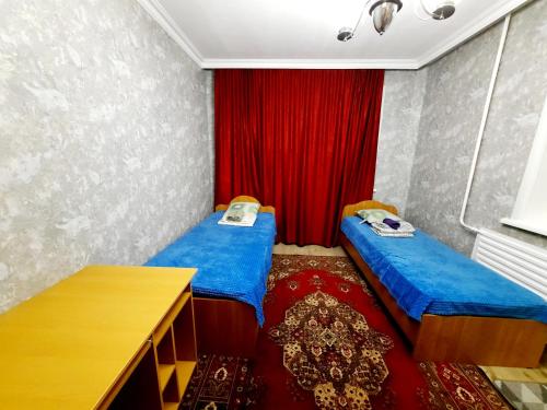 Habitación con 2 camas y cortina roja. en 2 комнатная квартира Назавбаева 34, en Pavlodar