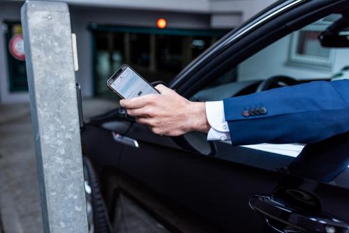 a man in a suit holding a cell phone in a car at Princess No3 Self Check-In Plochingen bei Stuttgart in Plochingen