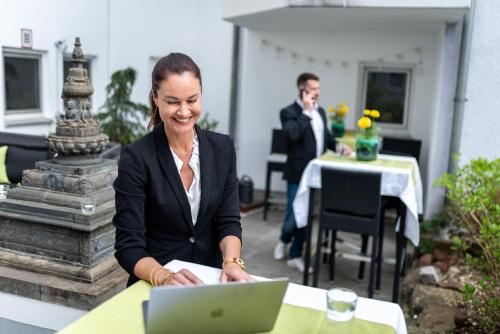 Eine Frau, die an einem Tisch mit einem Laptop sitzt. in der Unterkunft Hotel Princess Self Check-In in Plochingen