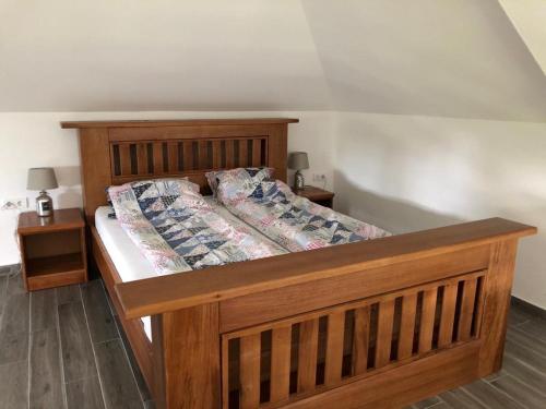 een houten bed in een kamer met 2 nachtkastjes bij Vila DORA in Divčibare