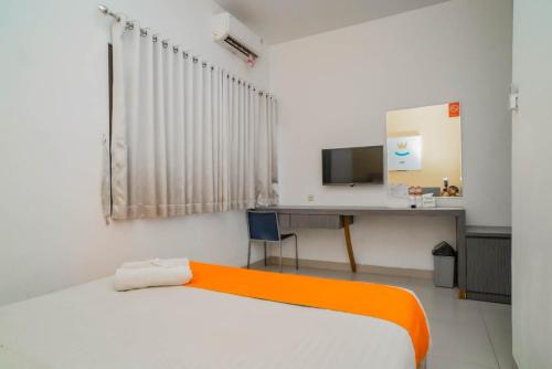 Dormitorio con cama, escritorio y TV en Sans Hotel Widarasari Cirebon en Cirebon