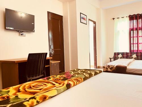 a bedroom with a bed and a desk and a television at Residence Inn Homestay in Shimla