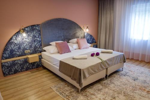 1 dormitorio con 1 cama grande y cabecero grande en Ditlin Apartmanok en Pápa
