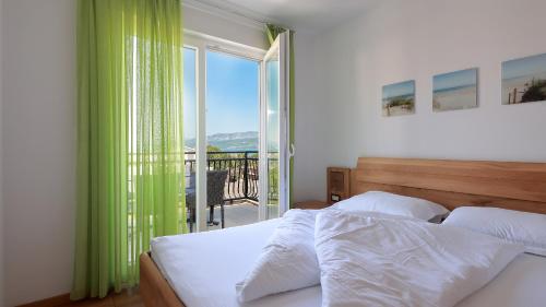 a bedroom with a bed and a balcony with a view at Cool Šilo Appartement Resort in Šilo