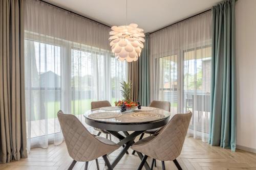 a dining room with a table and chairs and a chandelier at Vila „Perkūnas“ in Palanga