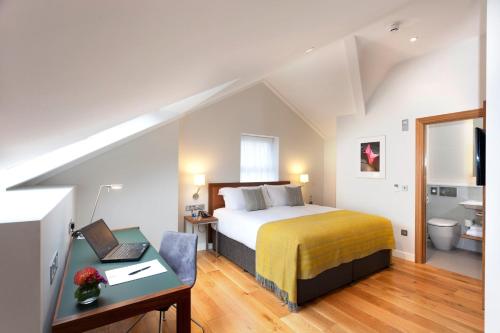 a bedroom with a bed and a desk with a laptop at PREMIER SUITES Dublin, Ballsbridge in Dublin