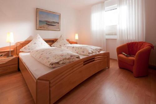 a bedroom with a large bed and a chair at Ferienhaus Mien Huske in Norderney