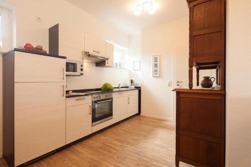 uma cozinha com electrodomésticos brancos e pisos em madeira em Ferienhaus Mien Huske em Norderney