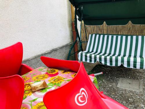 duas cadeiras vermelhas, uma mesa e um banco em Casa di Aristide em Erba