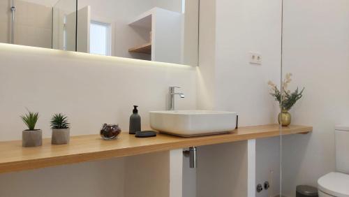 ein Badezimmer mit einem weißen Waschbecken auf einer Holztheke in der Unterkunft Lujoso Apartamento en San Cristobal de la Laguna in La Laguna