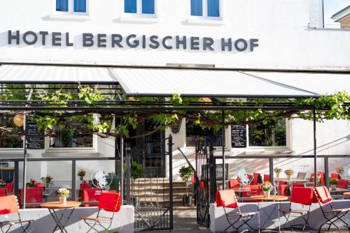 um restaurante com mesas e cadeiras em frente a um edifício em Storyhotel Bergischer Hof Königswinter em Königswinter