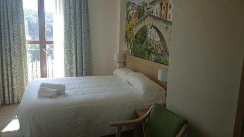 a bedroom with a bed and a chair and a window at Hostal Rural San Andrés in Torres del Río