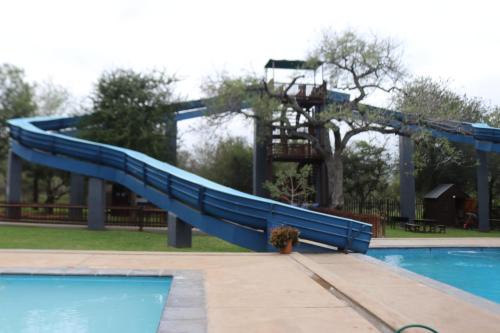 a slide in a swimming pool with a playground at Unogwaja Rest in Marloth Park