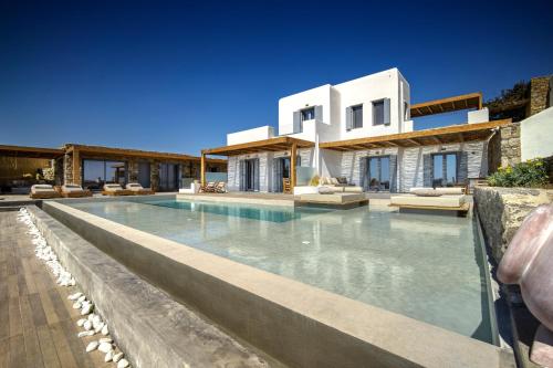 a villa with a swimming pool in front of a house at KK Mykonos Village in Mýkonos City