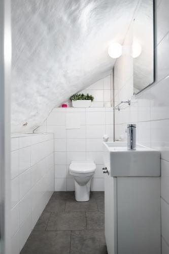 a white bathroom with a toilet and a sink at Hotell Skeppsbron in Stockholm