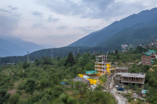 a group of buildings on a hill with mountains at Whoopers Hostel Manali in Manāli
