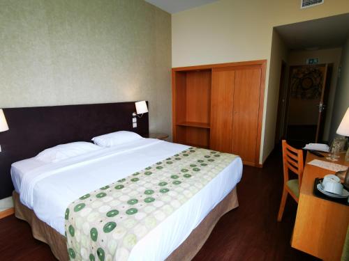 a bedroom with a large bed and a desk with a table sidx sidx at Hotel Da Montanha in Pedrógão Pequeno