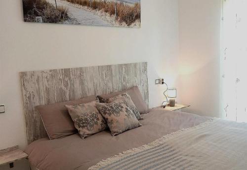 1 dormitorio con cama con cabecero de madera y almohadas en Nice apartment in a wonderful area, en Villacosta