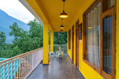 a yellow house with a balcony with a table at Whoopers Hostel Manali in Manāli