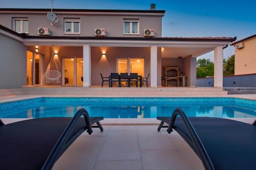 a villa with a swimming pool in front of a house at Villa MAAS in Loborika for 10 persons in Loborika