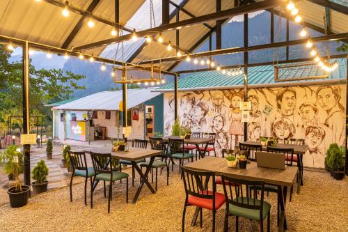 a restaurant with tables and chairs and a mural at Whoopers Hostel Manali in Manāli