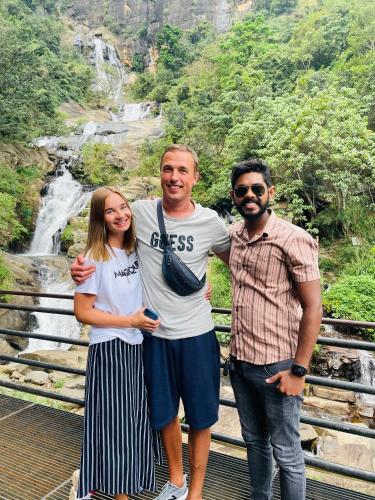 three people standing on a bridge in front of a waterfall at Shan Star Weligama in Weligama