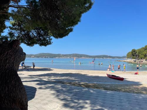 a beach with a bunch of people in the water at Mobile Home BARTOL de LUX in Biograd na Moru