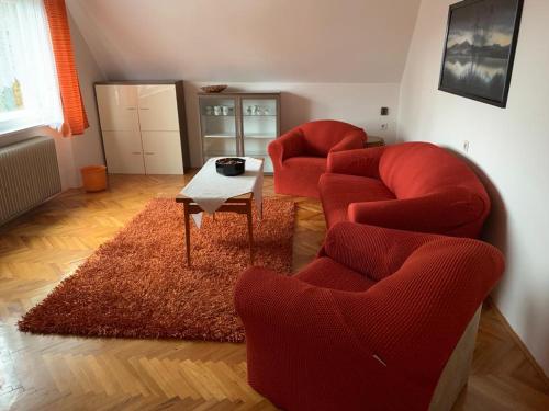 Svratka的住宿－apartman Luník，客厅配有2把红色椅子和1张桌子