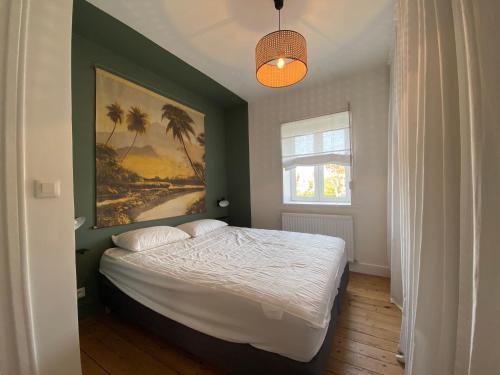 a bedroom with a bed with a painting on the wall at La Saumonerie - Charmante maison a 200m de la plage de Wimereux in Wimereux