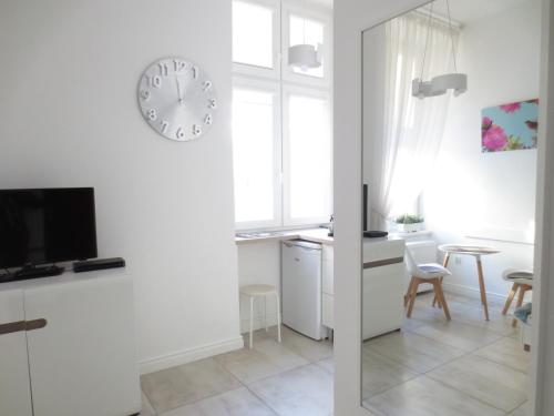 um quarto branco com uma secretária e um relógio na parede em Lovely apartment in the heart of the Old Town em Gdansk