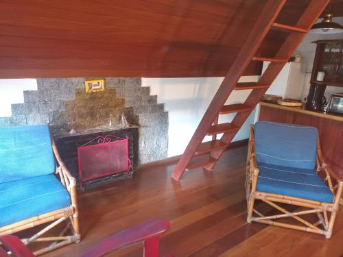 two chairs in front of a fireplace with a ladder at Hospedaria Bela Vista do Vale in Lumiar