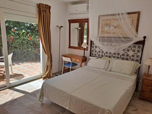 een slaapkamer met een bed, een bureau en een raam bij Finca Batan in Mijas