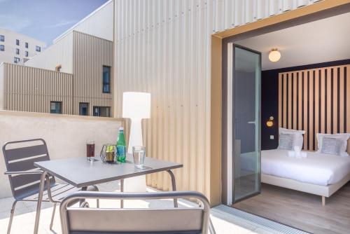 a balcony with a table and chairs and a bed at The Originals Résidence Le Monde Paris Ivry Confluence in Ivry-sur-Seine