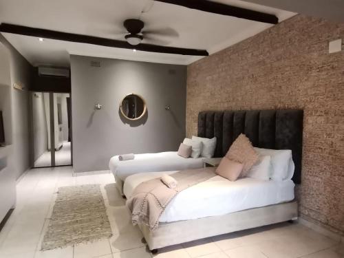 a bedroom with two beds and a brick wall at Umtamvuna River Lodge in Port Edward