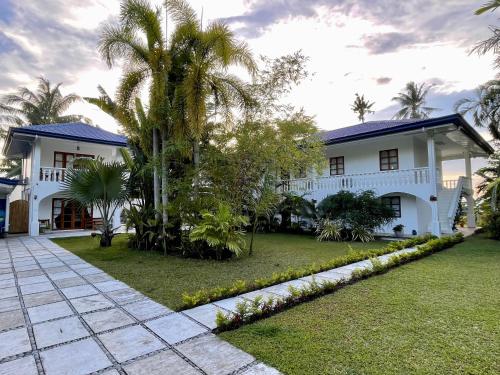 a white house with palm trees in the yard at Agoho Resort in Mambajao