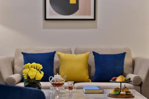 a living room with a couch with blue and yellow pillows at voco Al Khobar by IHG in Al Khobar