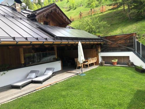 a backyard with a wooden deck with chairs and an umbrella at Cèsa Prinoth in Campitello di Fassa