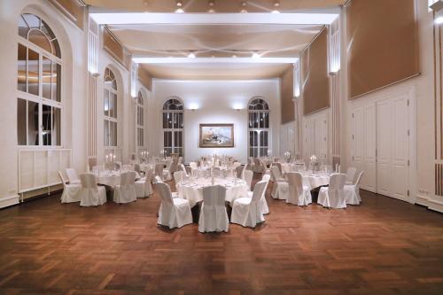 a large room with white tables and white chairs at Hotel Kieler Yacht-Club in Kiel
