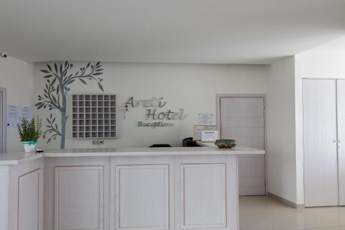 a kitchen with white cabinets and a sign on the wall at Areti Hotel in Agia Galini