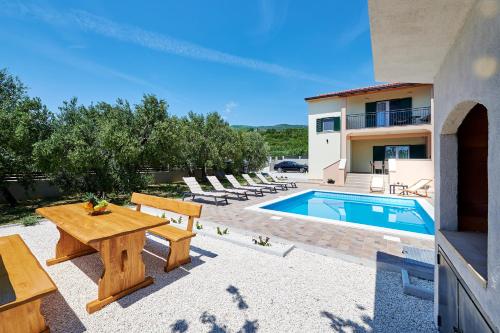 een patio met een tafel en stoelen en een zwembad bij Villa Lilly in Kaštel Novi