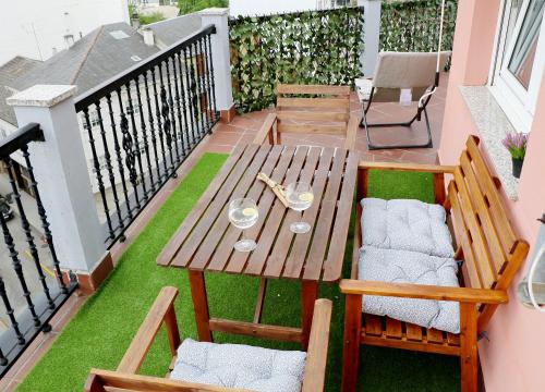 una mesa de madera y sillas en un balcón con césped en ÁTICO DUPLEX CREDENCIAL, en Sarria