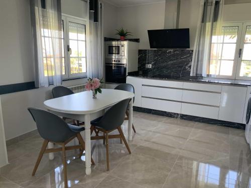 a kitchen with a white table and chairs and a counter at Apartamentos Casa Carin in Cadavedo