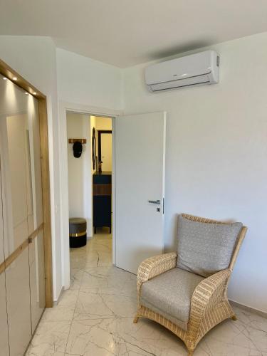 a living room with a chair and a white wall at Luce del Sole in Montepaone Lido