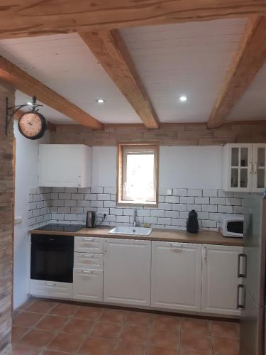 a kitchen with white cabinets and a sink and a window at Hygge chaloupka v horách in Český Jiřetín