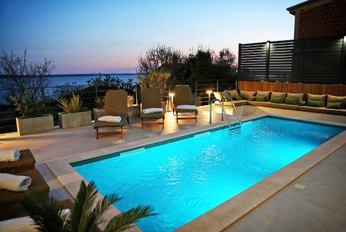 - une piscine avec des chaises et une terrasse donnant sur l'océan dans l'établissement Villa Seabatical, à Ražanac