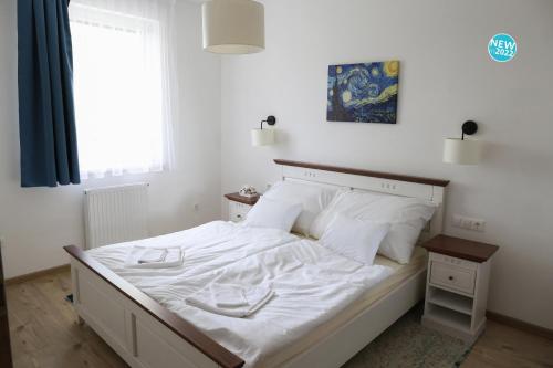 a bedroom with a bed with white sheets and a window at St.Gotthard Apartman in Szentgotthárd