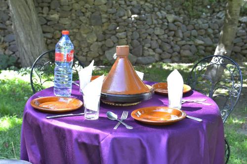 einem lila Tisch mit Tellern und einer Flasche Wasser in der Unterkunft IMLIL VALLEY Garden in Imlil