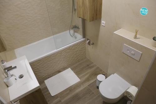 a bathroom with a toilet and a tub and a sink at St.Gotthard Apartman in Szentgotthárd