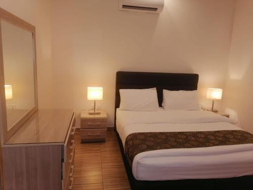 a bedroom with a bed and a desk with two lamps at Al-Ahlam Hotel Apartments in Aqaba